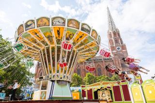 Menschen im Kettenflieger - im Hintergund die Kirche Mariahilf